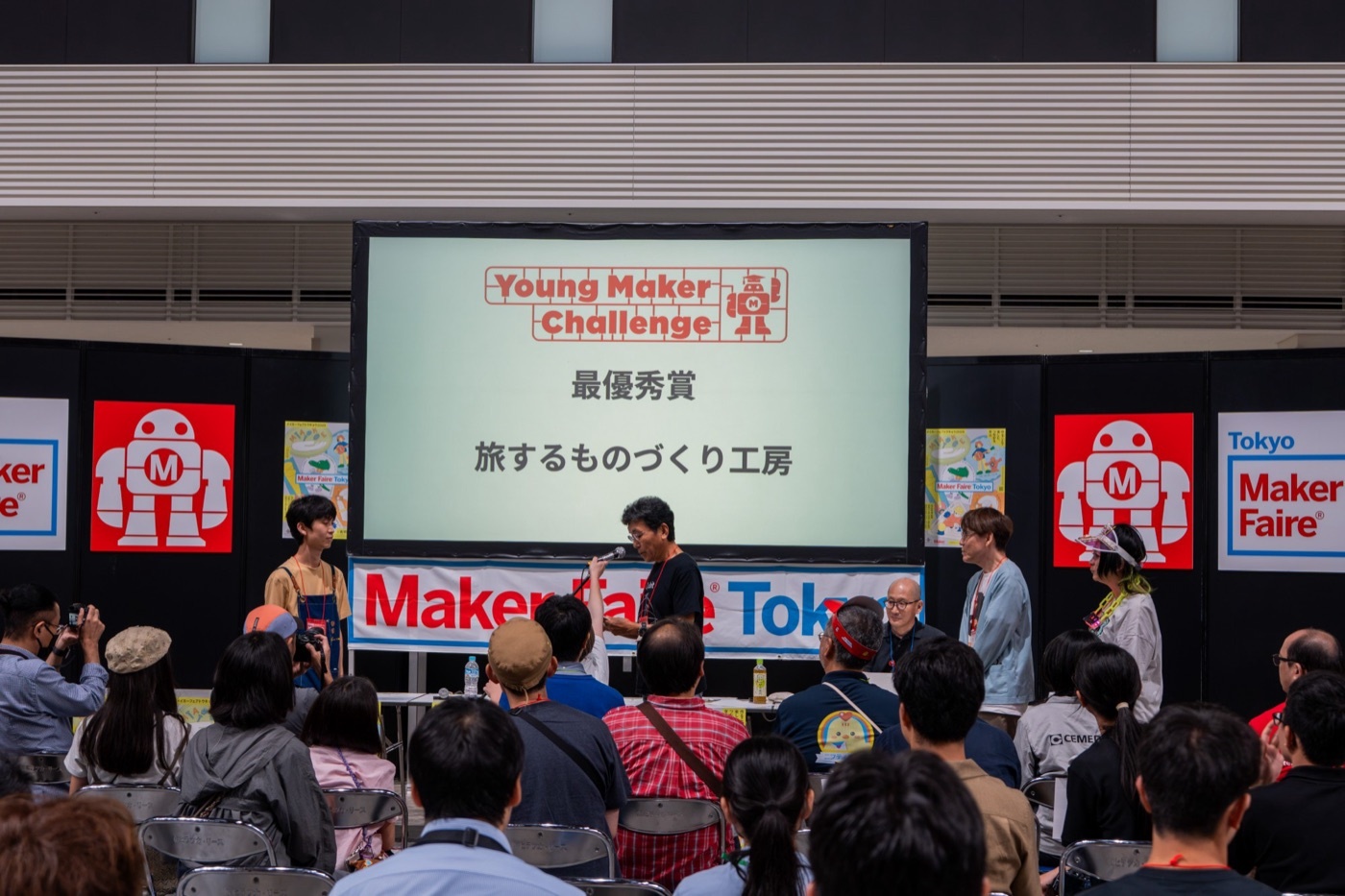 Young Maker Challenge 2026 の表彰式。スクリーンに「最優秀賞 旅するものづくり工房」と映っている