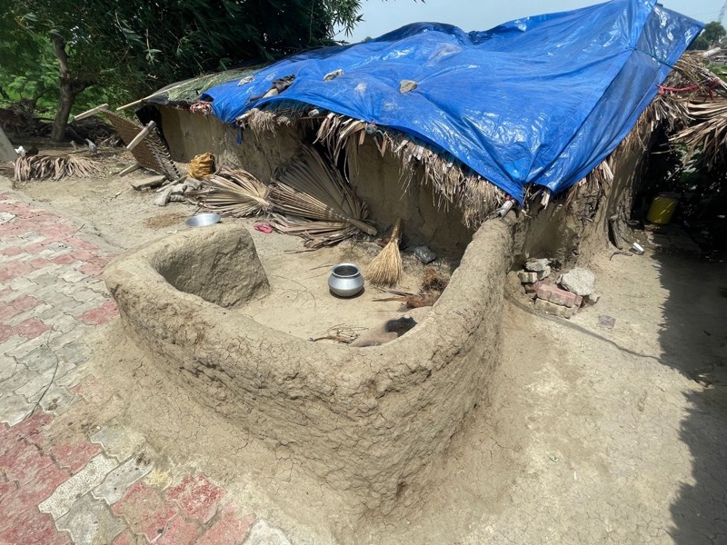 インド・ブッタガヤで出会った土の家。土でこねたかまどの向こうに、青いシートをかけた屋根の家が見える